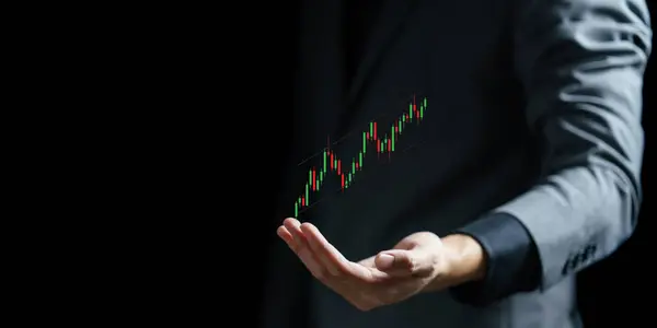 Karanlık bir arkaplanda bir grafik tutan işadamı eli.