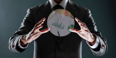 Elinde bir grafikle beyaz kağıt tutan bir iş adamı.