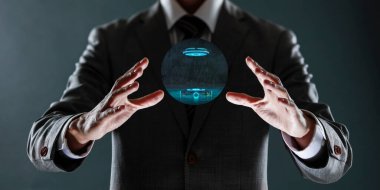 Mavi takım elbiseli bir işadamı elinde parlak bir ampulle elini açık tutuyor.