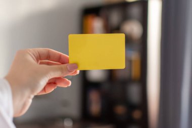 Bir kadının eli sarı bir kredi kartı tutar.