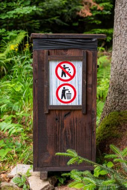 Ormandaki ahşap çöp kutusu. Ormana çöp atılmasını yasaklayan uyarı işareti