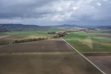 Bulutlu bir gökyüzünün altındaki tarlaların ve tarlaların havadan görünüşü