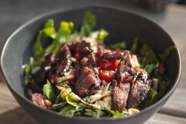 Karanlık bir kasede lezzetli biftek salatası.