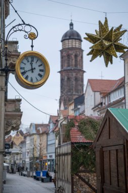 Arka planda kilise kulesi olan tarihi bir Avrupa kasabasında sokakta bir saat.