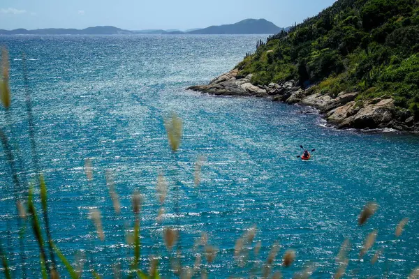 Kayalık sahil şeridinde kayalıklar üzerinde berrak, parlak mavi deniz.