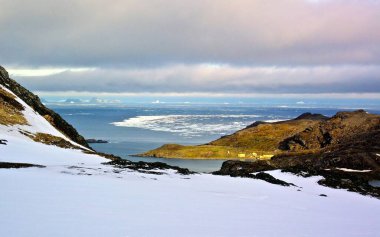 Karlı ve dağlı Norveç manzarası, deniz, fiyort ve güneş, güzel bir manzara.