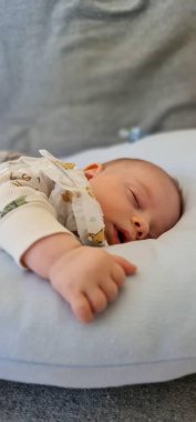 Yumuşak bir yastıkta huzur içinde uyuyan bir bebek. Yüzündeki dingin ifade ve sarılıp yatış şekli huzur ve huzur veriyor. Çevre sıcak ve sakin..