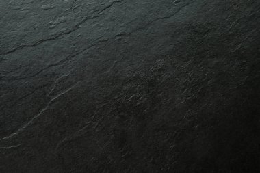 Yukardan aşağıya doğru çekilen doğal siyah taş dokunun yakın çekimi. Yüzey, görünüşte katmanlı desenler ve organik çatlaklarla kaplıdır, tasarım, modelleme veya yemek fotoğrafçılığı için ideal bir arka plan ya da doku olarak. En küçük, boş alan m