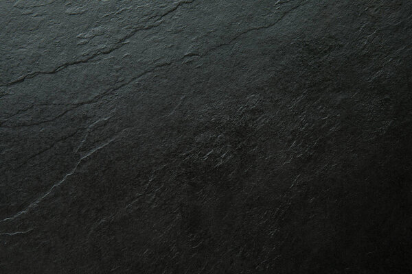 Крупный план природной черной текстуры из камня, полученной сверху вниз. Поверхность матовая с видимыми слоистыми узорами и органическими трещинами, идеально подходит в качестве фона или текстуры для дизайна, макетов или пищевой фотографии. Минимальное, пустое пространство m