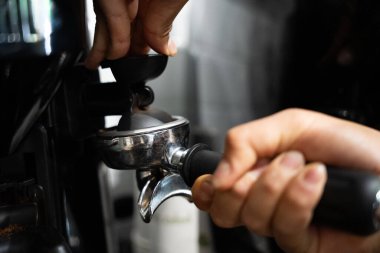 Baristalar el yordamıyla portatif filtreye kahve dolduruyor..