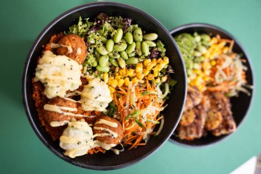 Yeşil arka planda izole edilmiş, falafel, mısır, edamame ve yeşilliklerle vejetaryen dürtme kasesi..