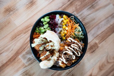 Sebzeli, pirinçli, soslu renkli bir kase, ahşap masaya izole edilmiş, üst manzaralı..