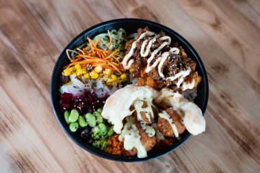 Sebzeli, pirinçli ve çıtır çıtır soslu poke kasesi, üst manzara, ahşap arka planda izole edilmiş..