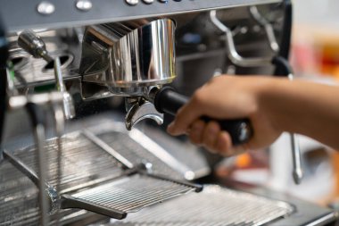 Barista espresso makinesine portafilter yerleştiriyor, ön görüş, kahve dükkanının arka planında izole edilmiş..