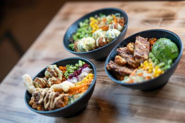 Izgara et ve sebzeli üç kase, ön manzara, ahşap arka planda izole edilmiş..