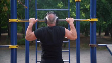 Glikoz izleyici sensörlü bir adam barfiks çekiyor.