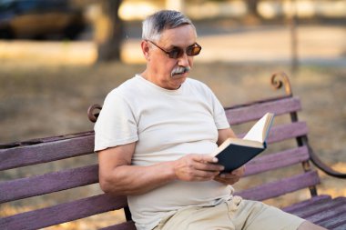 Park bankında kitap okuyan son sınıf öğrencisi.
