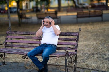 Yaşlı adam kulaklıkla müzik dinliyor.