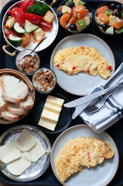 Siyah arka planda birçok yemeğin kahvaltısı, çırpılmış yumurta, ekmek, tereyağı, sebze, meyve, peynir 