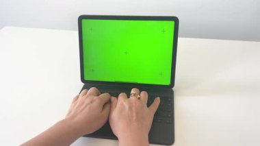 Bir kadının elleri tablet üzerinde klavyeyle yeşil ekranda çalışıyor. . 