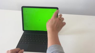 Bir kadının elleri tablet üzerinde klavyeyle yeşil ekranda çalışıyor. . 