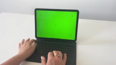 Bir kadının elleri tablet üzerinde klavyeyle yeşil ekranda çalışıyor. . 