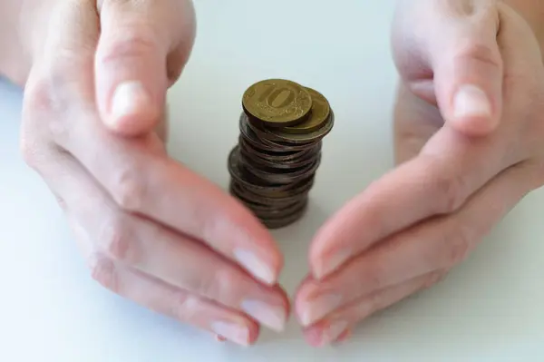 Eller nazikçe madeni para yığınını kapatır, tasarrufların korunması, mali güvenlik. 