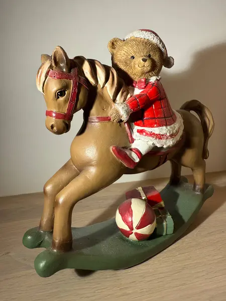 Christmas toy bear on rocking horse with gifts, festive holiday decoration. 