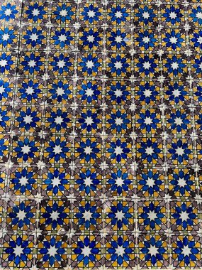 Tekrarlayan mavi, sarı ve beyaz yıldız şekilli karoların parlak, çetrefilli mozaiği simetrik bir desen oluşturur..