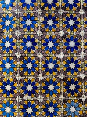 Tekrarlayan mavi, sarı ve beyaz yıldız şekilli karoların parlak, çetrefilli mozaiği simetrik bir desen oluşturur..