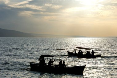 Bir teknede gün batımını seyreden haydutların silueti.