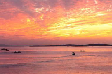 Glyaz Gölü üzerinde turuncu gün batımı ve balıkçı tekneleri