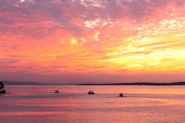 Glyaz Gölü üzerinde turuncu gün batımı ve balıkçı tekneleri