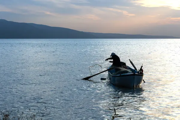Gölde balıkçı ağıyla çalışan balıkçı silueti..