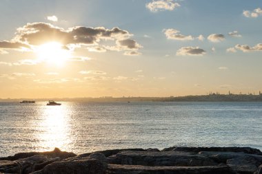 Denizin üzerinde gün batımı ve bir teknenin silueti