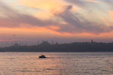 Mavi caminin silueti ve güneş batarken ve tarihi yarımadada denizin arka planında Ayasofya.