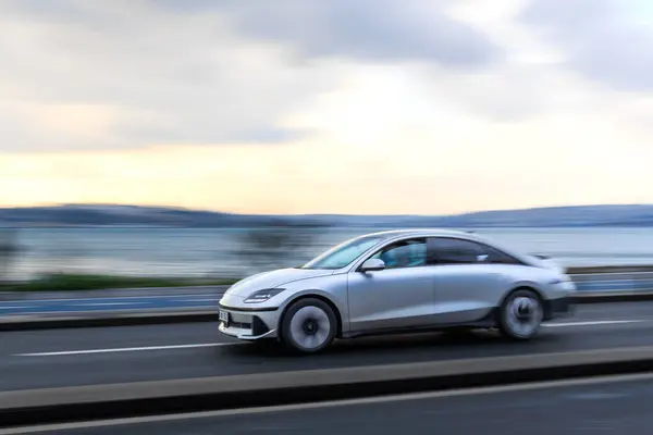 Metalik gri araba yol üzerinde. Panning tekniği ve hız kavramı var..