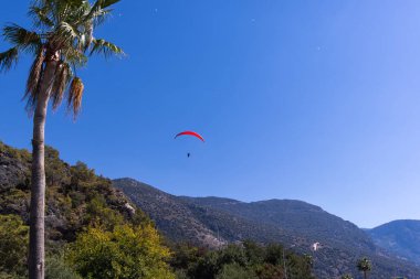 Paraglider dağların üzerinde açık mavi gökyüzünde uçuyor, Fethiye, Mugla