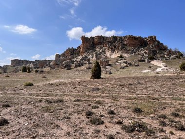 Eski yerleşim yerlerinin kalıntıları eski kaya oluşumları ve mavi gökyüzünün altındaki ağaçlar.