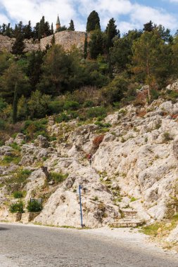 Bir adam kayalık yoldan Alanya 'daki tepenin zirvesine doğru yürüyor.