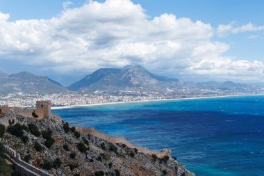 Güneşli bir havada Alanya şehri ve tepe ve bulutlardan oluşan antik duvarlar.