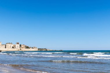 Dalgalar kıyıya vuruyor ve uzaktaki eski limana bakıyor, Mersin.