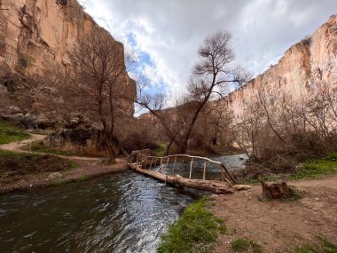 Akan nehirde ahşap bir köprü ve vadide ağaçlar