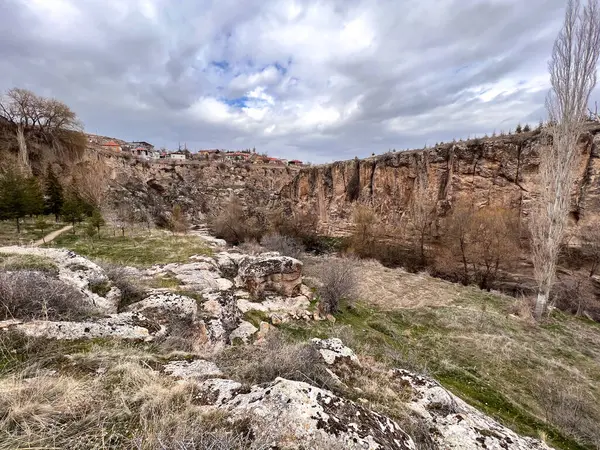 Bulutlu bir günde kayalık uçurumun tepesindeki evler ve tepelerdeki kayalar