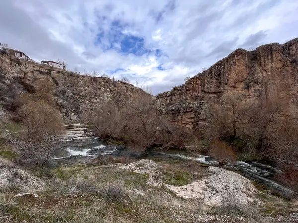 Vadide akan nehir suları dağların arasında ve vadinin tepesindeki evler bulutlu bir günde