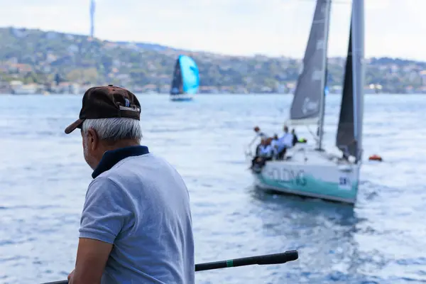 a fisher man is catching fish on the coastline of Bosphorus while 24th Bosphorus Cup is running on 20 September 2025