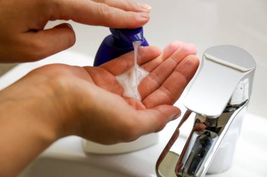 Mikrop ve bakterileri önlemek için antibakteriyel sabunla ellerini yıkıyorsun.