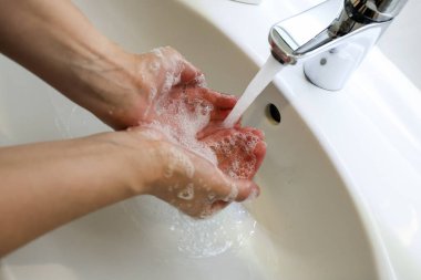 Banyo lavabosunda sabunla ellerini yıkamak, hijyen kavramı.