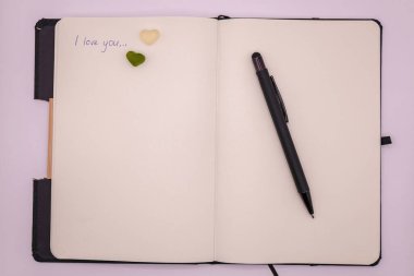 Mesajını, kalbini ve beyaz arka planda siyah bir kalemi olan bir defter. Sevgililer Günü