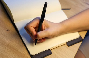 Deftere kalemle yazan bir kadının el yazısını kapat.